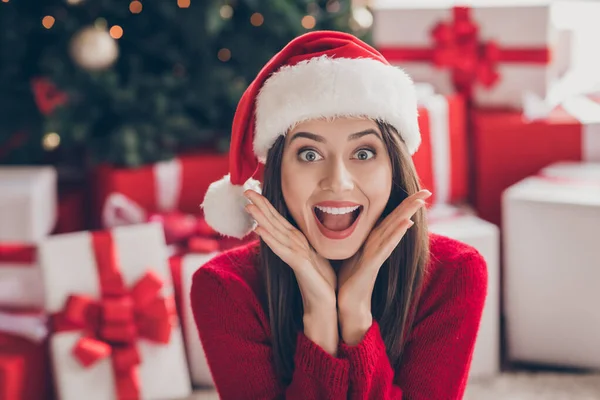 Heyecanlı, şirin bayan kutuları kolları açık ağızlı Noel Baba başlıklı kırmızı kazaklı ev dekore edilmiş Noel Baba oturma odasında — Stok fotoğraf