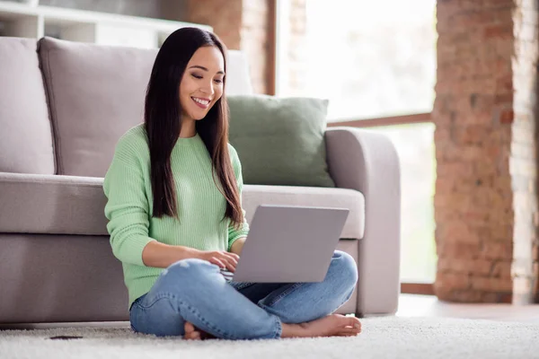 Profilo completo foto laterale di positivo coreano ragazza sedersi pavimento tappeto gambe incrociate piegato a piedi nudi lavoro laptop remoto hanno formazione web meeting in casa al chiuso — Foto Stock