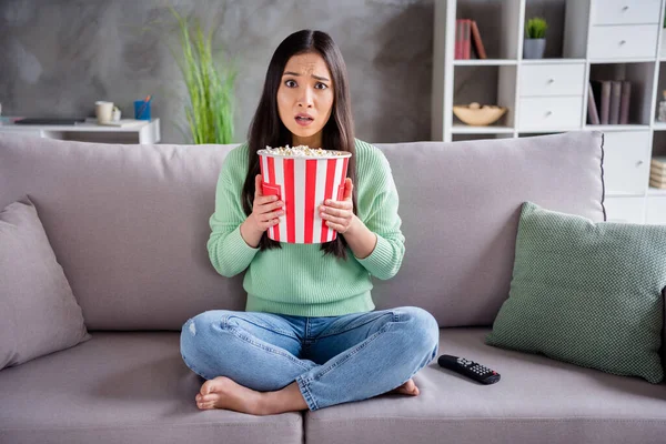 걱정하는 중국 소녀가 앉아 있는 사진, 신발 다리를 건너는 공포 영화는 집안에 큰 팝콘 상자를 들고 있다. — 스톡 사진