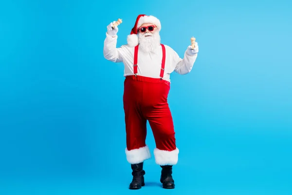Pełny rozmiar zdjęcie fajnego hipstera Santa Claus z dużym brzucha trzymać sól papryka x-mas Wigilia obiad przygotować styl noszenia modne szelki ogólne nakrycia głowy odizolowany niebieski kolor tło — Zdjęcie stockowe