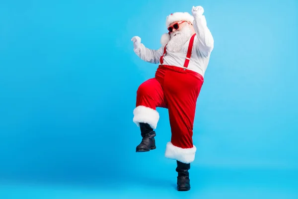 Pełna długość zdjęcie fajne hipster tłuszczu Santa Claus taniec x-mas Boże Narodzenie tradycja dyskoteka nosić szelki ogólne okulary przeciwsłoneczne buty izolowane na tle niebieskiego koloru — Zdjęcie stockowe