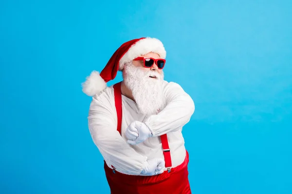 Foto van opa grijze baard verhogen handen dansen clubbing vuisten discotheek slijtage santa claus x-mas kostuum bretels zonneglas wit shirt hoofdmode handschoenen geïsoleerde blauwe kleur achtergrond — Stockfoto