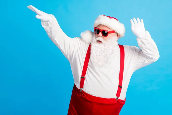 Foto di Babbo Natale moderno danza x-mas festa tradizione indossare bretelle copricapo pantaloni isolati su sfondo di colore blu — Foto Stock