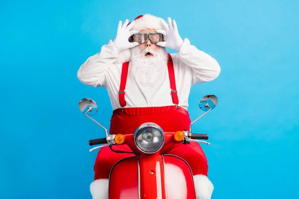 Foto van gekke stijlvolle vet santa claus onder de indruk x-mas kerst magie rijden stijl trendy scooter dragen bril aanraken handen bretels overalls cap geïsoleerd over blauwe kleur achtergrond — Stockfoto