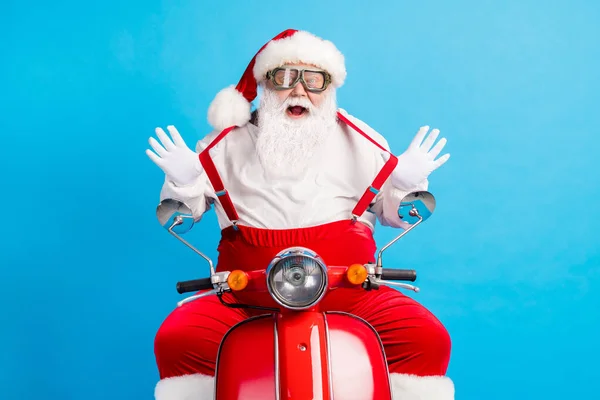 Fénykép a stílusos modern vicces kövér mikulás lovagolni motorkerékpár húzza nadrágtartó x-mas karácsonyi vidám utazás viselet stílus divatos overál szemüveg fejfedő elszigetelt kék szín háttér — Stock Fotó