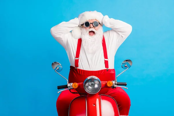 Verbazingwekkende stijlvolle moderne kerstman met grijze witte haarbaard rijden motor x-mas kerst traditie partij aanraken handen hoofdmode bretels overalls geïsoleerde blauwe kleur achtergrond — Stockfoto