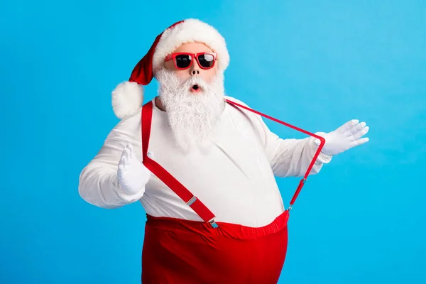 Zdjęcie dziadka szara broda ręce grać paski otwarte usta niespodzianka nosić Santa Claus x-mas kostium szelki sunglass biały koszula rękawice ochronne odizolowany niebieski kolor tło — Zdjęcie stockowe