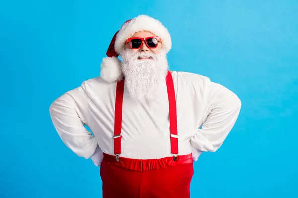 Zdjęcie funky Santa Claus z dużym brzuchem umieścić ręce x-mas Boże Narodzenie tradycja duch stworzenie nosić nakrycie głowy okulary ogrodniczki odizolowane nad niebieskim pastelowym tle kolor — Zdjęcie stockowe
