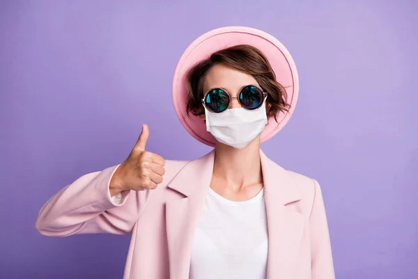 Foto de senhora em máscara médica fecial usar blazer rosa boné óculos mostrando como uma mão isolado cor violeta fundo — Fotografia de Stock