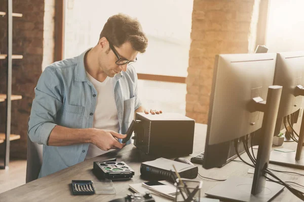 Fotografie zaměřený chlap software podpora master sit desk opravy pevný disk operační systém nosit džíny košile denim na pracovní stanici — Stock fotografie