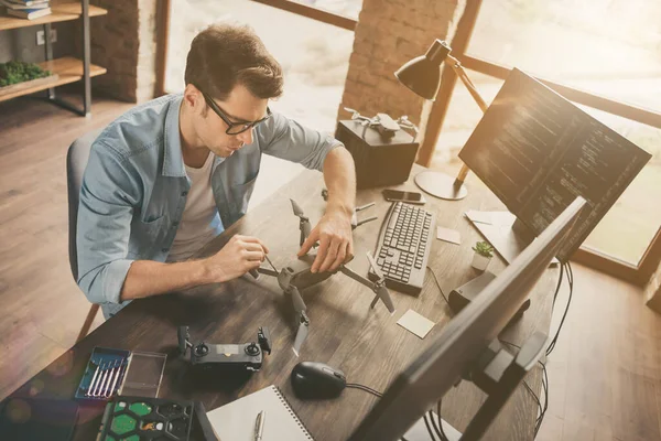 Hoge hoek bekijk profiel zijkant foto van gerichte man zitten bureau reparatie helikopter spelen drone gebruik apparatuur in moderne kantoor werkplek — Stockfoto