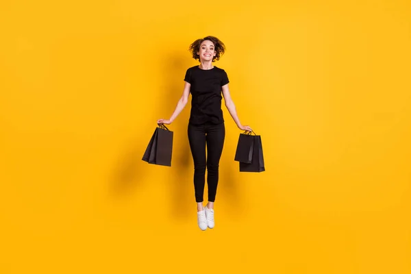 全身上下尽收眼底迷人欢快时髦的女孩背着包裹跳着便宜货店孤立的明亮的黄色背景 — 图库照片