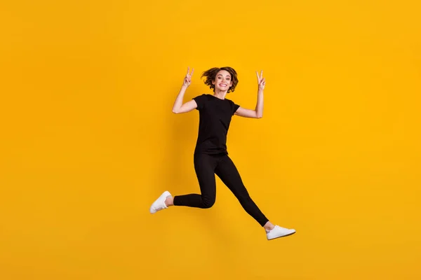 Full length body size view of attractive funky cheerful girl jumping having fun showing v-sign isolated bright yellow color background — Stock Photo, Image