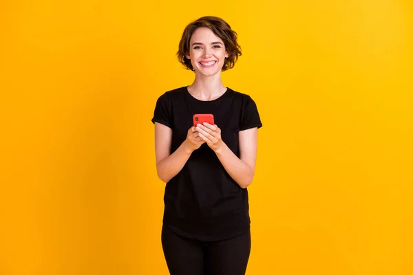 明るい黄色の背景に隔離されたデバイスアプリのsmmを使用して手に持つ魅力的な陽気な女の子の肖像画 — ストック写真