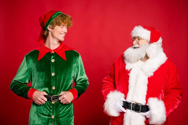 Photo de deux hommes santa claus rousse elfe regarder les uns les autres bras ceinture usure x-mas costume chapeau spécifications isolé couleur rouge fond — Photo