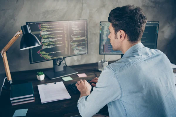 Rear back behind view portrait of his he nice attractive focused geek guy typing css analyzing cyberspace security building at modern industrial interior style concrete wall work place station — Stock Photo, Image