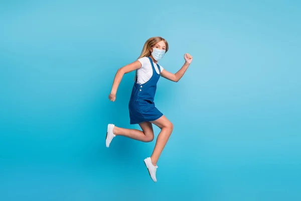 Foto de tamaño completo de divertida chica rubia saltando correr desgaste gripe máscara camiseta mini vestido zapatillas aisladas de color azul de fondo —  Fotos de Stock