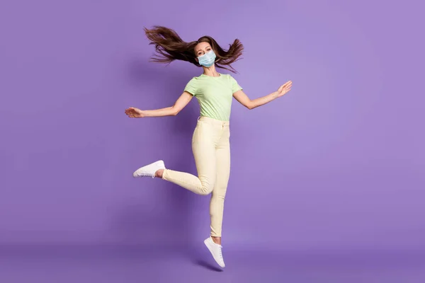 Visão de comprimento total da linda menina despreocupada pulando tendo máscara de desgaste divertido isolado sobre brilhante brilho vívido vibrante cor lilás violeta fundo — Fotografia de Stock