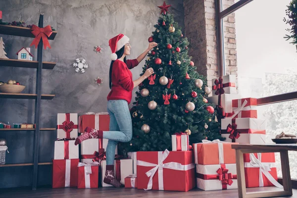 원문 기사보기 미국 소녀가 산타 클라우스 모자를 쓰고 크리스마스 트리에 장난감을 걸고 실내에서 크리스마스를 보내는 모습 x-mas 성탄절 장식 장식을 하고 있는 모습 — 스톡 사진
