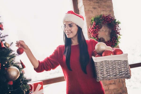 산타 클라우스의 머리쓰개를 입은 소녀의 사진은 크리스마스 날마다 실내에 있는 x-mas 장식이 있는 상록수 위에 걸려 있다. — 스톡 사진
