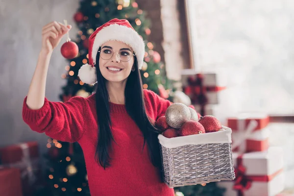 Zdjęcie dziewczyny w nakryciach głowy Świętego Mikołaja powiesić pudełko bombkowe Boże Narodzenie w domu w domu z dekoracji x-mas — Zdjęcie stockowe