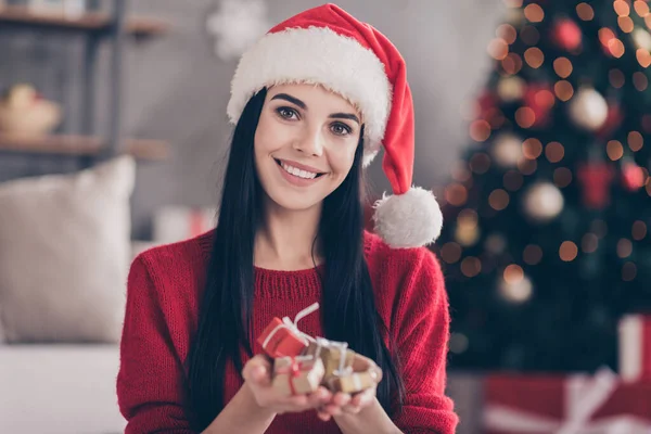 Noel Baba şapkalı pozitif bir kızın portresi evde küçük bir hediye kutusu ve Noel süsleri barındırıyor. — Stok fotoğraf