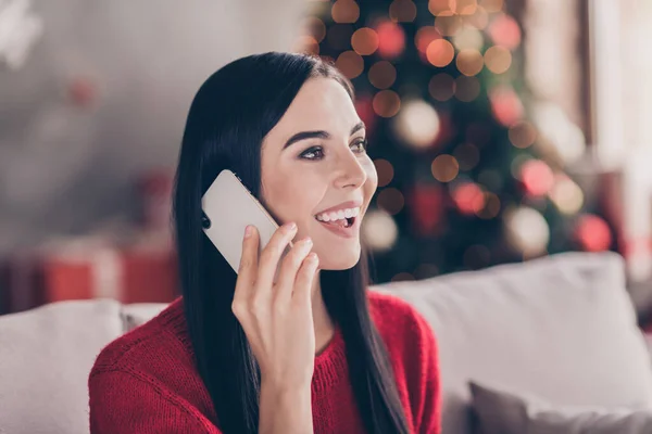 Foto de encantadora jovem segurar telefone olhar lado falar desgaste camisola vermelha na sala de estar decorada dentro de casa — Fotografia de Stock