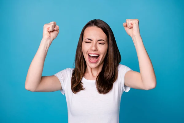 Foto de atractiva señora bastante divertida buen humor levantar los puños celebrar logro gritando en voz alta la competencia extática ganar desgaste casual camiseta blanca aislado color azul fondo —  Fotos de Stock