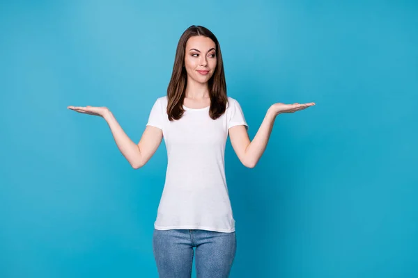 Foto de senhora atraente bom humor mantenha as palmas das mãos abertas braços mostrando selecionar escolher novidade dois produtos venda desconto compras olhar uma mão desgaste branco t-shirt jeans isolado azul cor fundo — Fotografia de Stock