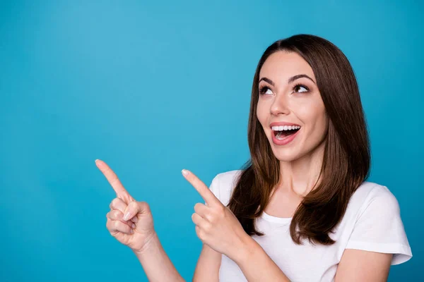 Primeros planos de la atractiva señora divertida buen humor dirigir los dedos hacia arriba espacio vacío presentando novedad banner venta ropa casual blanco camiseta aislado color azul fondo — Foto de Stock