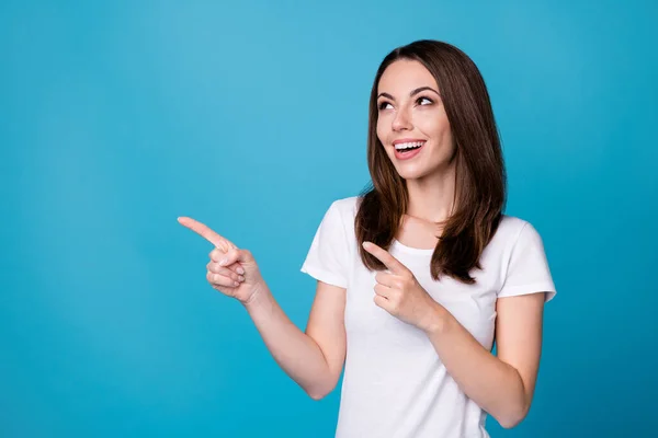 Foto de atractiva dama encantadora buen humor dedos directos boca arriba espacio vacío que muestra la demostración de la novedad banner desgaste casual camiseta blanca aislado fondo de color azul — Foto de Stock