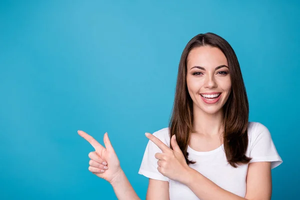 Foto av attraktiv ganska rolig charmig dam gott humör regissera fingrar sida tomt utrymme visar nyhet slitage casual vit t-shirt isolerad blå färg bakgrund — Stockfoto