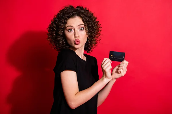 Fénykép imádnivaló vicces hullámos hölgy öltözött alkalmi fekete ruha gazdaság hitelkártya ajkak duzzadt elszigetelt piros szín háttér — Stock Fotó