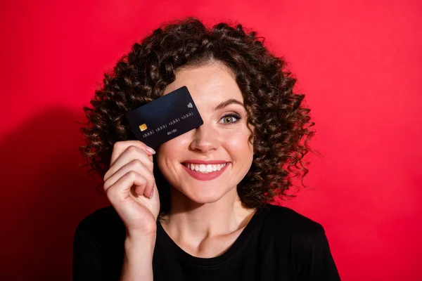 Foto de engraçado complicado ondulado senhora vestida casual preto roupa fechar olho cartão de crédito isolado cor vermelha fundo — Fotografia de Stock