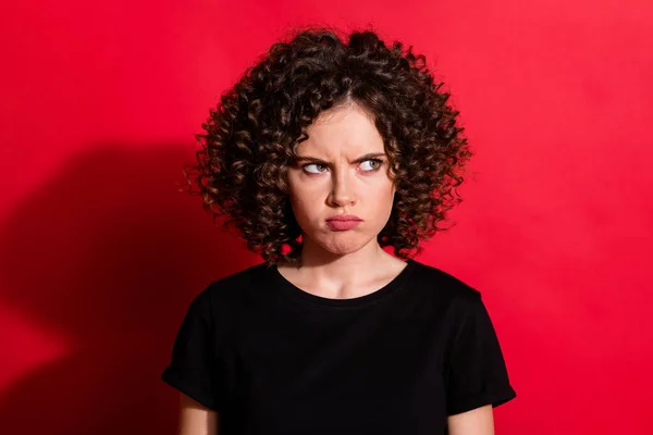 Close-up portret van vrij gek beledigd golvend-harig meisje fronsen kijken opzij geïsoleerd over helder rood kleur achtergrond — Stockfoto