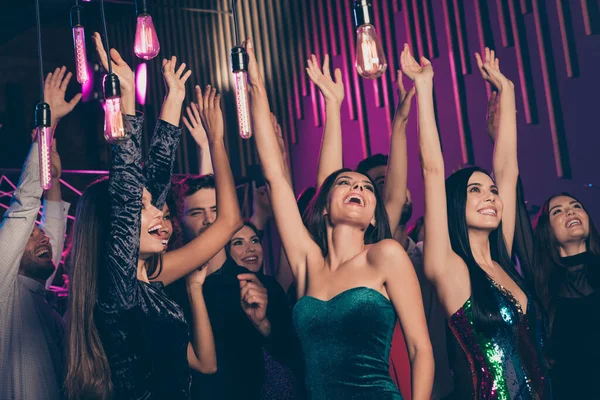 Фотографія друзів, які танцюють разом на корпоративній вечірці в нічному клубі з неонами, що святкують новий рік разом у стильному святковому одязі — стокове фото