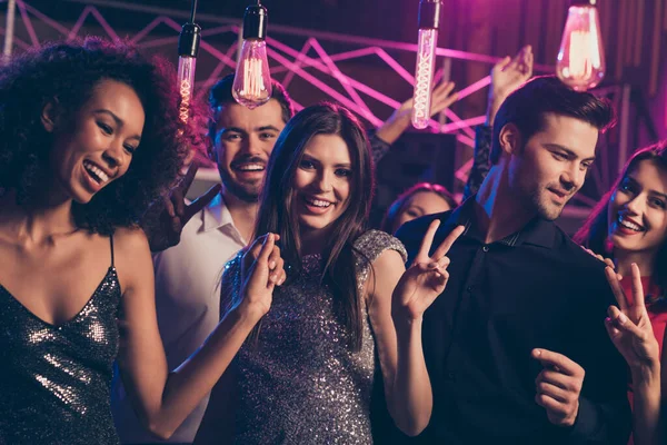 Foto retrato de personas emocionadas juntas mostrando signos de v bailando en el club nocturno con lentejuelas formales vestido brillante —  Fotos de Stock