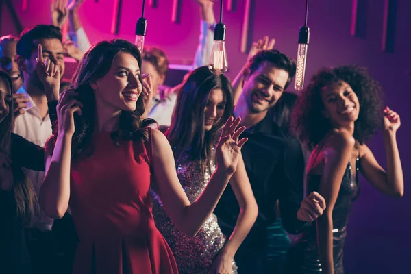 Foto retrato de chica de ensueño bailando junto con otras personas en el club nocturno en luz de neón rosa y azul en vestido rojo —  Fotos de Stock