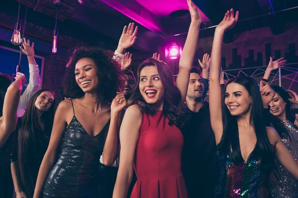 Фотопортрет збуджених молодих людей, які танцюють разом в нічному клубі дами в красивих червоних блискучих вишуканих елегантних сукнях — стокове фото