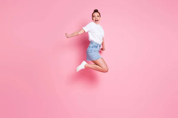 Foto de perfil de longitud completa de la señora loca funky bonito moño celebrar las vacaciones de verano a partir de saltar alto vuelo desgaste camiseta blanca mini falda calzado aislado color rosa fondo — Foto de Stock