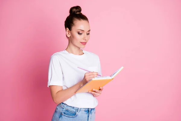 초점이 맞춰진 소녀가 책 숙제를 쓰는 사진은 핑크 색 배경에 고립 된 예쁜 옷을 입고 있다 — 스톡 사진