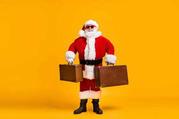 Foto de cuerpo entero de santa claus con barba x-mas Navidad víspera de viaje resto de equipaje de bodega desgaste cabeza roja gorra sunglass aislado sobre brillante brillo color fondo — Foto de Stock