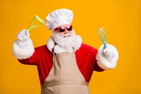 Foto von lustigen Weihnachtsmann in kulinarischen Chef Kopfbedeckung halten Geschirr vorbereiten X-mas frohes Neujahrsessen tragen Schürze isoliert über hellem Glanz Farbhintergrund — Stockfoto