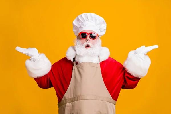 Photo of amazed santa claus with beard in chef cap hold hand compare x-mas christmas newyear magic cook meal discounts wear apron isolated bright shine color background — Stock Photo, Image