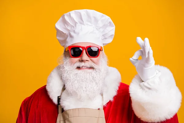素晴らしい奇跡のクリスマスのごちそう料理。シェフキャップのサンタクロースヘッドウェアショー明るい輝きの色の背景に隔離された大丈夫なサイン着用サングラス赤い衣装 — ストック写真