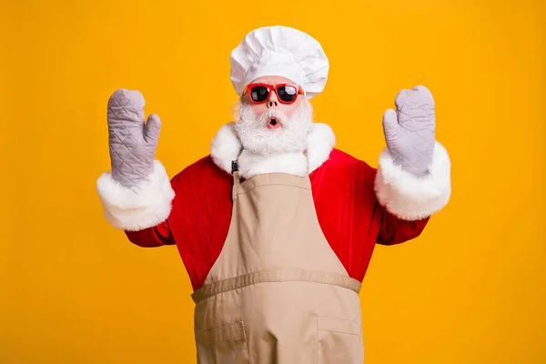 Zdjęcie zdezorientowany Santa dziadek szef kuchni nakrycia głowy piec gotowanie podnieść ręce rękawice otwarte usta próbował pomóc zrobił źle przenieść nosić czerwony kostium płaszcz okulary okulary fartuch izolowany żółty kolor tło — Zdjęcie stockowe