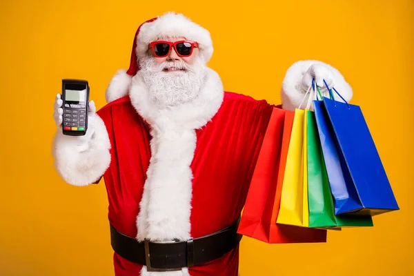 Çekici, neşeli, şişman Noel Baba 'sının portresi elinde bir şeyler taşırken dijital terminal perakende mağazası butik geçiş kartı izole parlak, parlak, parlak, parlak sarı arka plan. — Stok fotoğraf