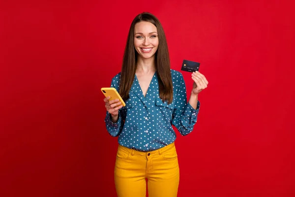 Portrait of attractive cheerful girl using device bank card web order isolated over bright red color background — Stock Photo, Image