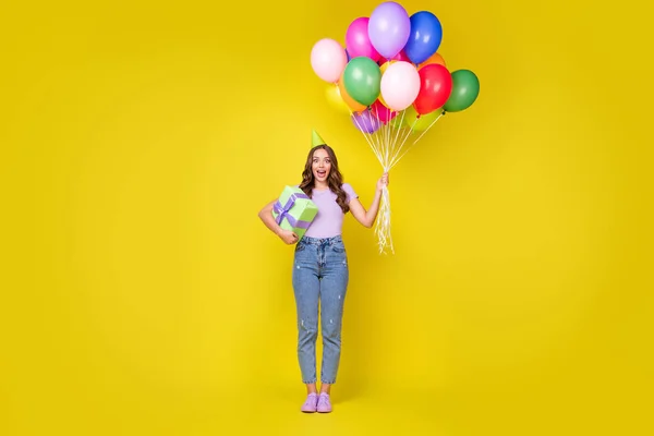 Vista completa del tamaño del cuerpo de la atractiva chica de pelo ondulado alegre asombrada sosteniendo bolas de racimo aisladas de color amarillo brillante fondo — Foto de Stock