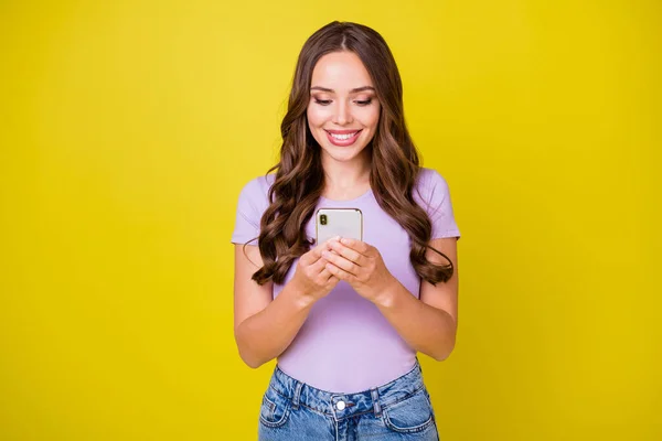 Retrato de atraente focado alegre menina de cabelos ondulados usando gadget smm post isolado sobre vibrante cor amarela fundo — Fotografia de Stock